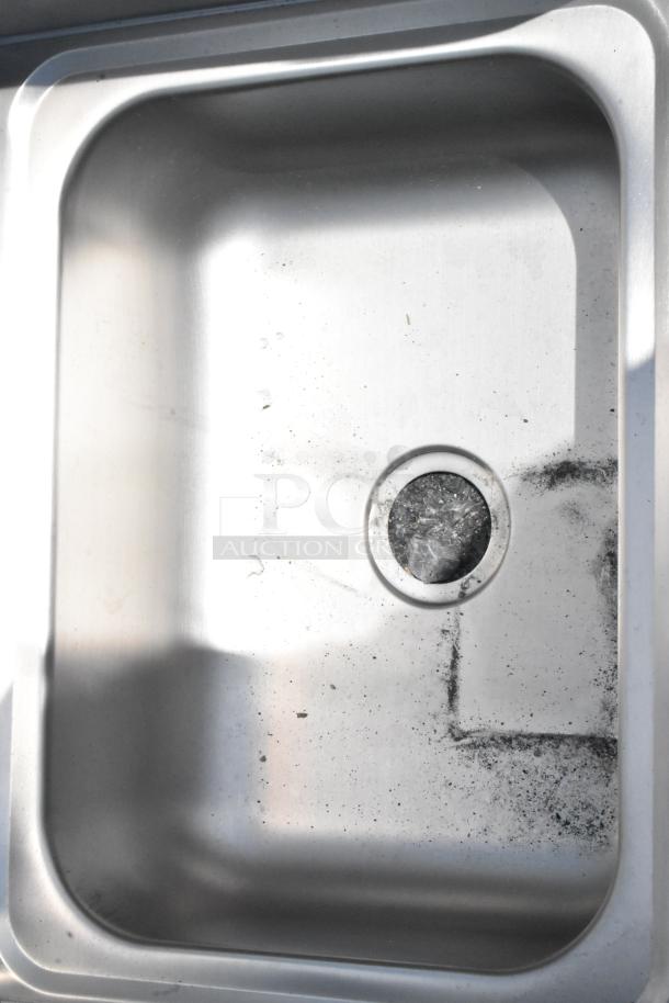 Stainless steel kitchen sink, rectangular, single basin, minor surface scratches, visible residue, used condition.