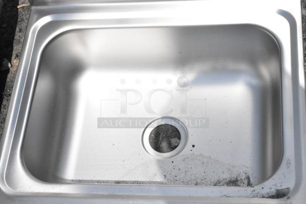 Stainless steel kitchen sink with single basin, visible dirt and wear, rounded edges, standard drain hole.