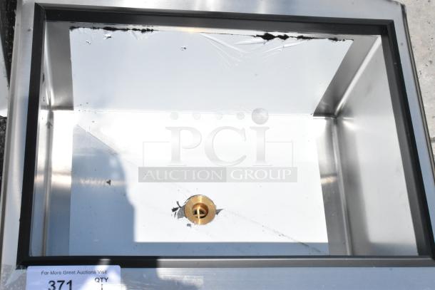 Rectangular stainless steel sink, lightly worn, with a central gold drain. Noticeable lining material at edges. Auction lot 371.