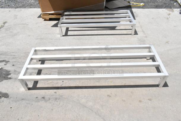 Two metal pallet racks, rectangular, white finish, in good condition. Ideal for industrial use or warehouse storage.
