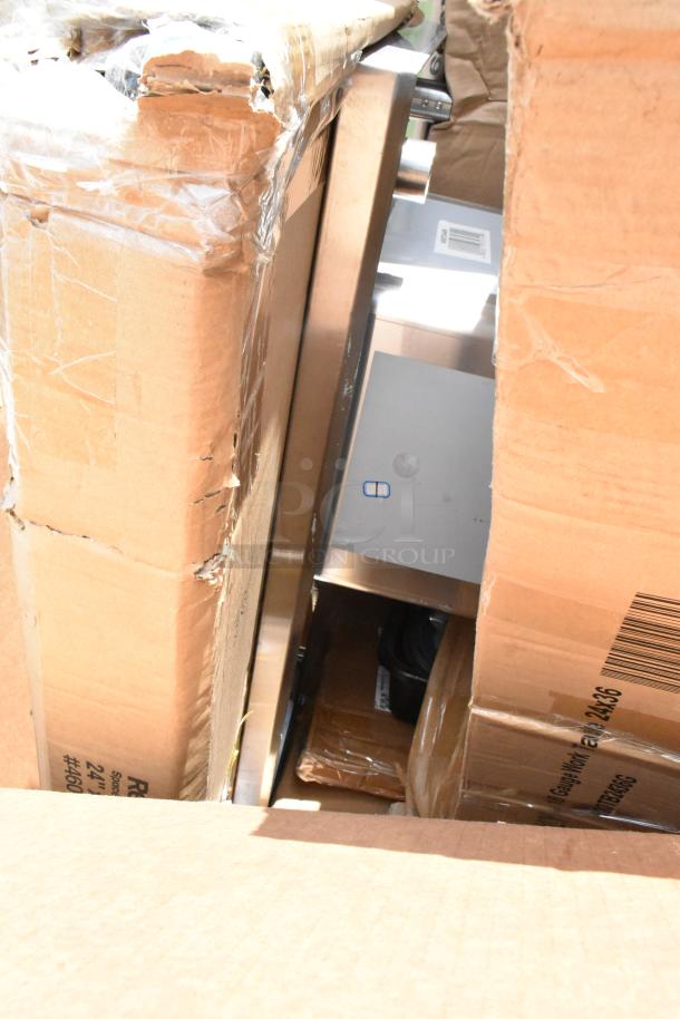 Cardboard boxes partially opened, revealing stainless steel appliance inside. Boxes show wear and tear, appliance appears intact.