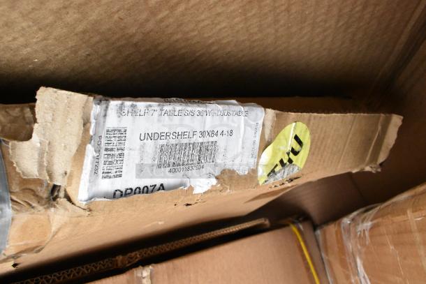 Cardboard box labeled "Undershelf 30x84 4-18," showing wear. Barcode and SKU DP007A visible, indicating a stainless steel table accessory.