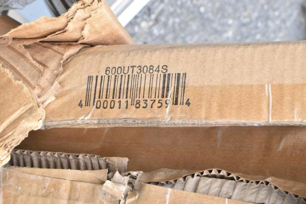 Cardboard box with visible barcode, "600UT3084S" marking, and slightly damaged edges.