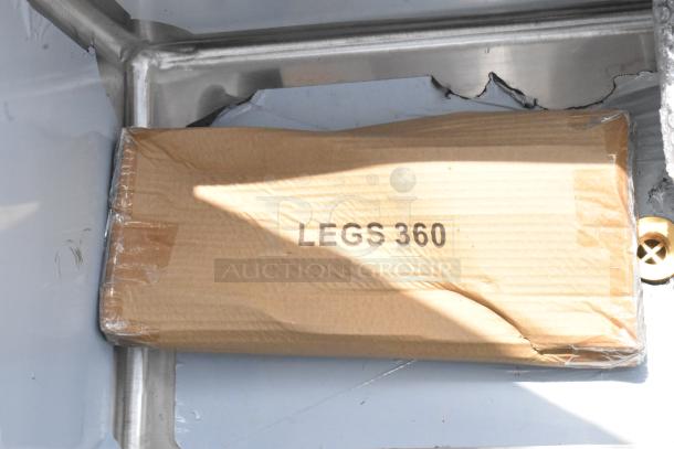 Box labeled "LEGS 360" in original packaging, slightly dented, against metal framing.