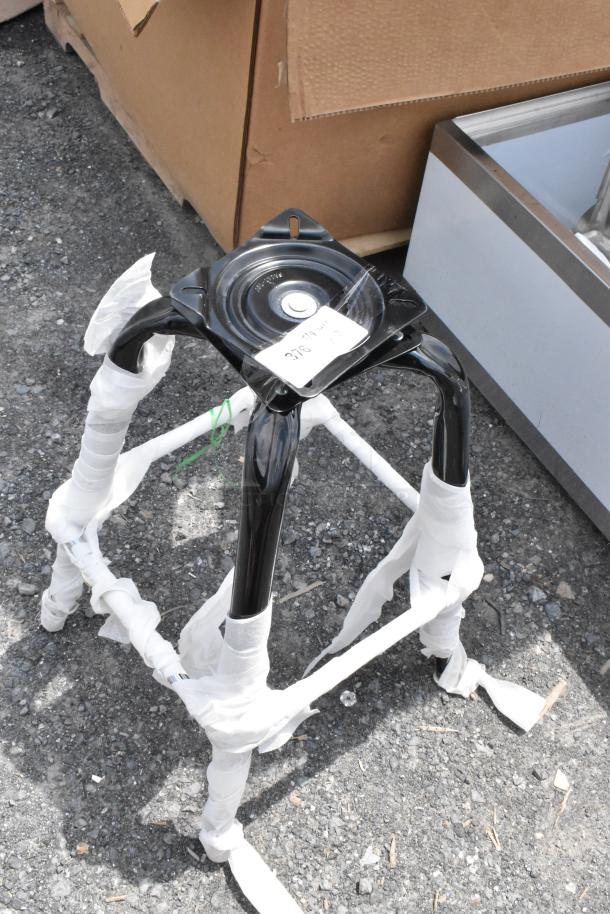 Black metal stool leg assembly, wrapped in protective padding. Top plate features a white tag indicating item number.
