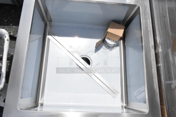 Stainless steel kitchen sink, square basin, modern design, includes drain opening, accompanied by a bracket and wrapped accessory.