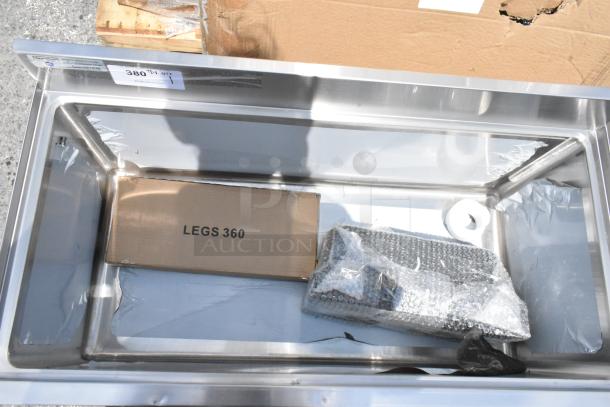 Stainless steel sink basin with cardboard box marked "LEGS 360," bubble-wrapped components, new condition, auction number tag.