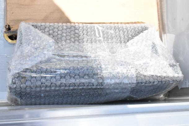 Item wrapped in bubble wrap on cardboard, partially unpacked. Condition unknown, potential electronics or fragile item.