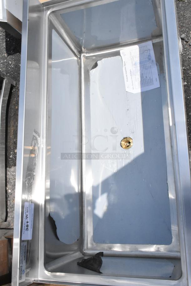 Stainless steel sink with visible scratches and a central drain hole. Attached label reads "38 1/N QTY."