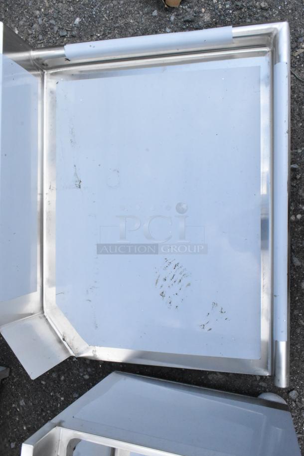 Stainless steel corner tray with raised edges, some surface marks, used condition, no visible labels or markings.