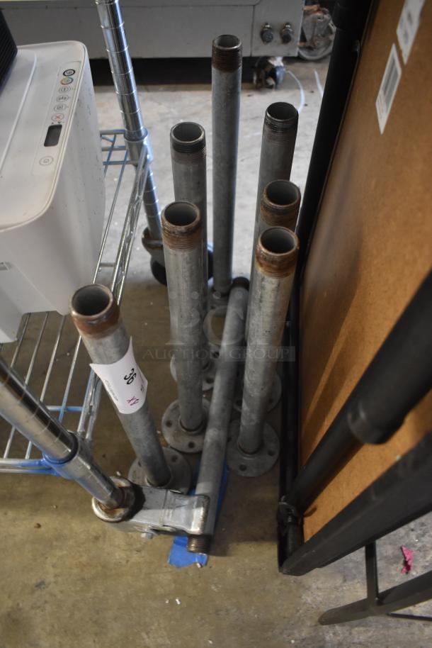 Metal pipes with threaded ends, various heights, some surface rust. White tag marked "36 XX" suggests lot or item number.