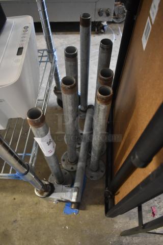 Metal pipes with threaded ends, various heights, some surface rust. White tag marked "36 XX" suggests lot or item number.