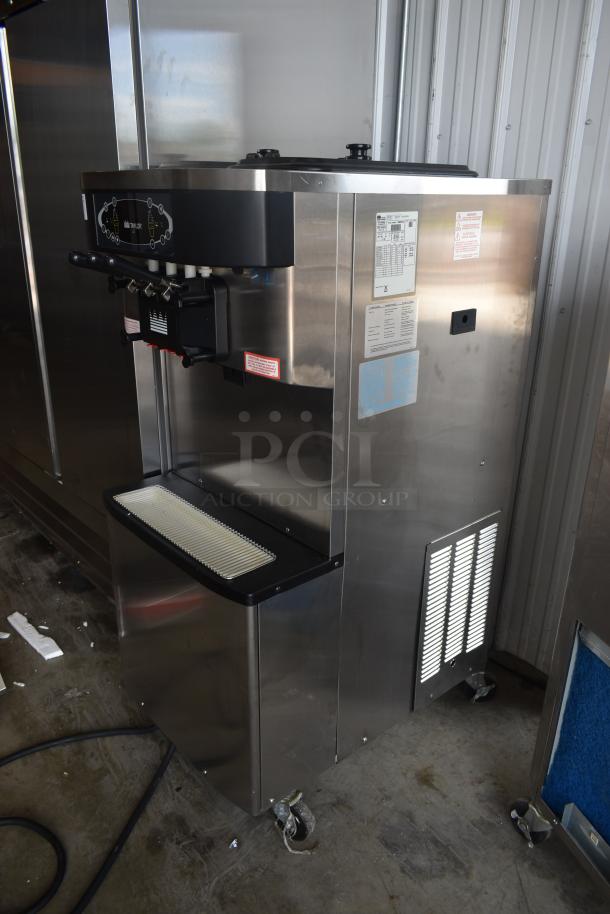 Commercial soft serve ice cream machine, stainless steel, dual dispensers, on wheels, visible labels with operating instructions.