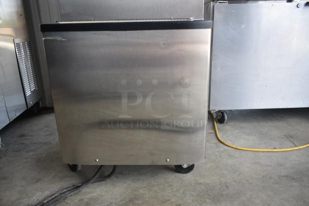 Commercial stainless steel refrigeration unit on wheels, shows slight surface wear, suitable for industrial kitchen use.