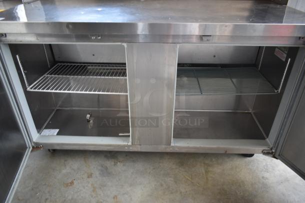 Stainless steel commercial storage unit with two open compartments, wire shelves, and a single label. Used, good condition.