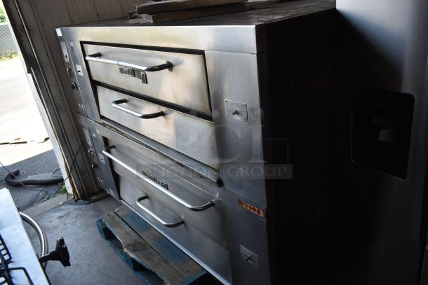 Commercial double-deck pizza oven, stainless steel, showing wear. Features temperature controls and visible manufacturer labels.