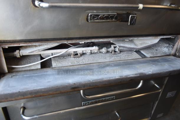 Commercial pizza oven interior, with metal components and dust, showing wear. No visible labels or markings.