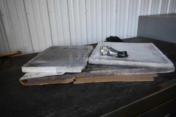 Two stone slabs and a metal coupling on a table, some wear and discoloration.