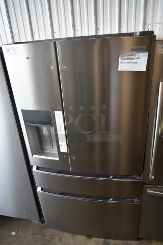 Stainless steel Frigidaire French door refrigerator, dual drawers, built-in water dispenser. Auction labels with details visible.