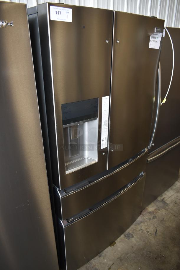 Stainless steel French door refrigerator with water dispenser, brand name partially visible, in good condition, auction tag on top.