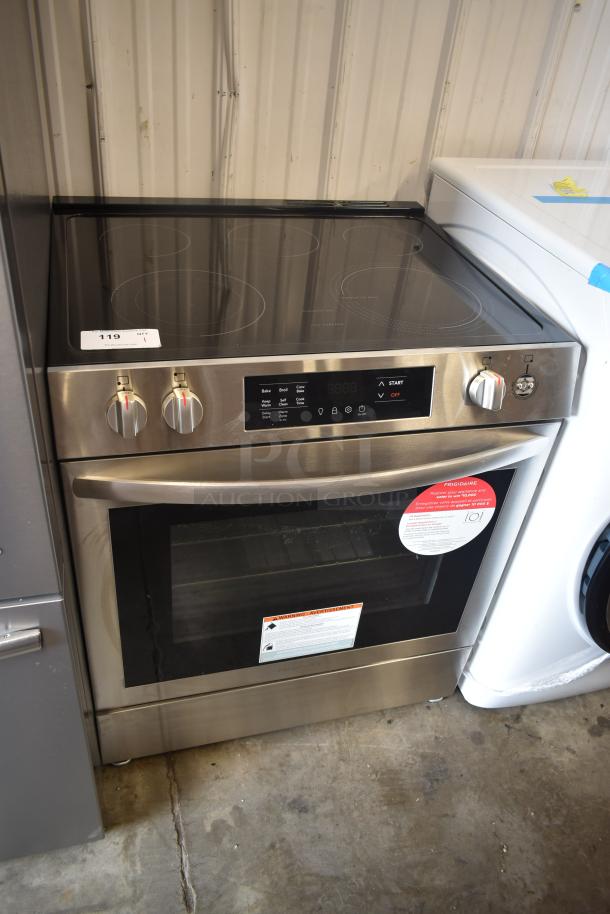 Frigidaire stainless steel electric range, 4-burner, glass top, digital control panel, and visible safety tags; excellent condition.