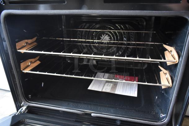 Black convection oven interior with two metal racks, protective cardboard inserts, and visible instructions. New condition.