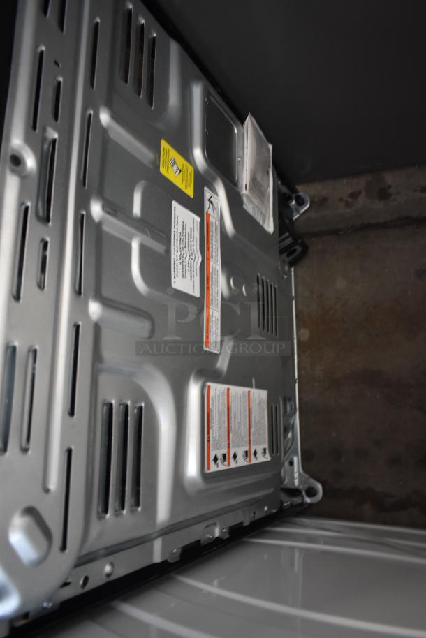 Metal appliance base with manufacturer labels and safety warnings, in new condition. Ventilation slots visible.