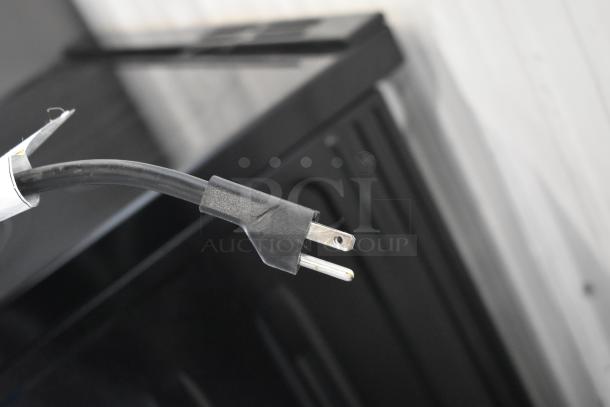 Black power cable with three-prong plug, attached tag indicating model information; cable appears in good condition.