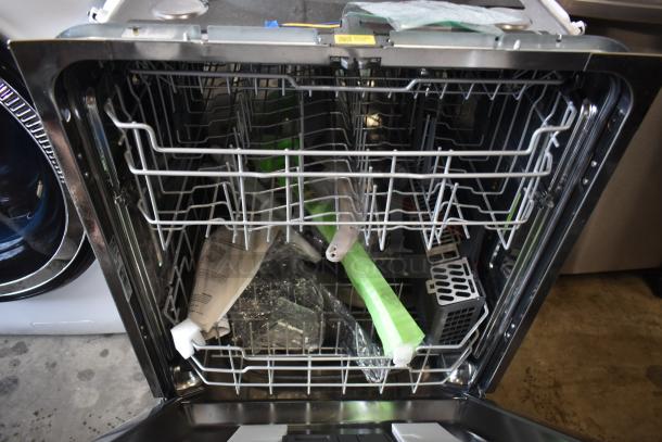 Open dishwasher showing interior racks, protective packaging, and instruction manual; appears new, ready for installation.