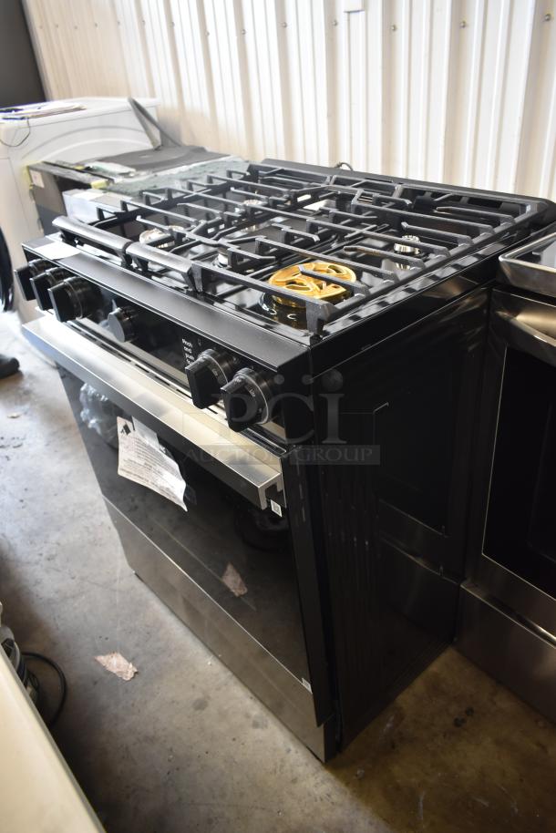 Black modern gas stove with five burners and control knobs. Stainless steel front. Good condition with attached manufacturer's label.
