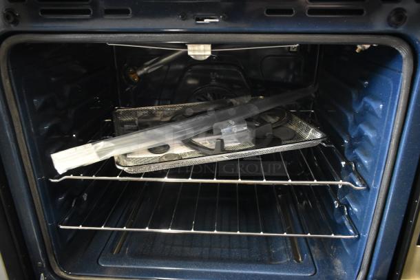 Blue interior electric oven with accessories inside, including racks, a metal tray, and bagged components. Unused condition.