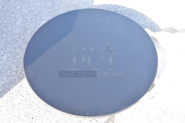 Round black tabletop, smooth surface, likely made of metal or laminate, in good condition with minor scratches.