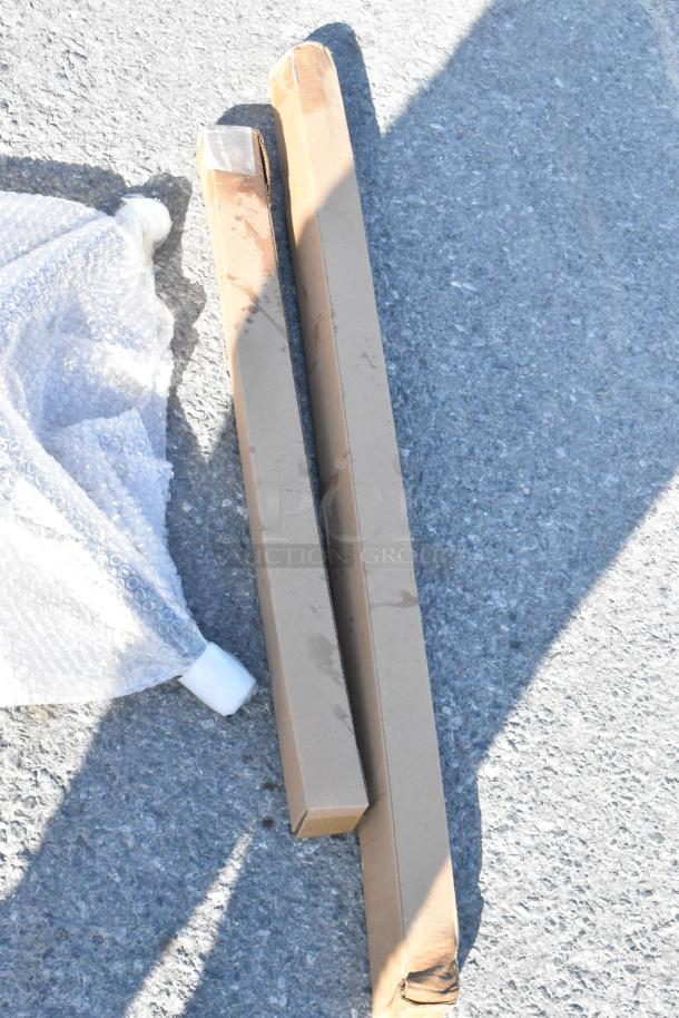 Two long, rectangular cardboard boxes and bubble wrap on pavement, indicating packaged items. Boxes show mild wear.