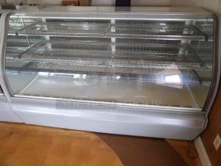 One Structural Concepts Curved Glass Refrigerated Bakery Display Case. 220 Volt. Curved Glass In Front, With 2 Rear Slide Doors, Lighted Donut Display Case, 4 Rack Powers on and works as should