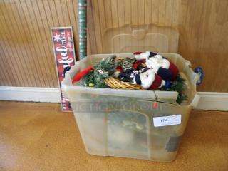 Plastic bin filled with Christmas decorations, including Santa figures and greenery, labeled "174."