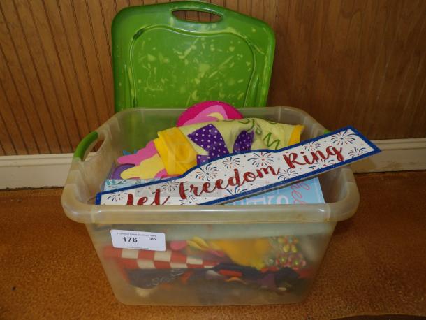 Clear plastic bin with assorted felt crafts, fabric decor, and a "Let Freedom Ring" sign, marked with auction label 176.