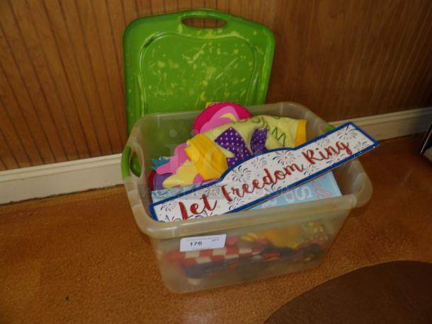 Clear storage bin with colorful felt crafts and a "Let Freedom Ring" sign. Bin marked with label "176."