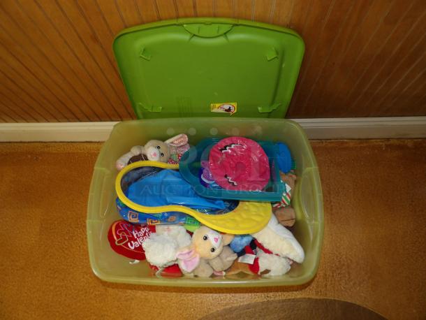 Green plastic storage bin with assorted plush toys, including a rabbit and Valentine's heart. Lid open, contents visible.