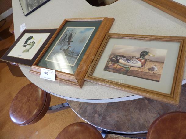 Three framed duck prints with oak frames on a table; label indicates auction lot number 183.