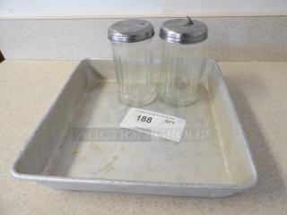 Aluminum baking tray with two clear glass shakers, metal lids, auction tag numbered 188. Tray shows wear.