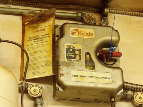 Kidde fire suppression system with pull pin and handle, labeled for operation. Visible wear and detailed usage instructions.
