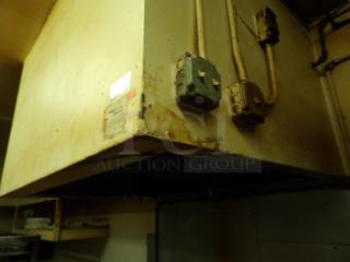 Industrial kitchen exhaust hood with electrical conduits. Visible wear and rust. Labels present but illegible.