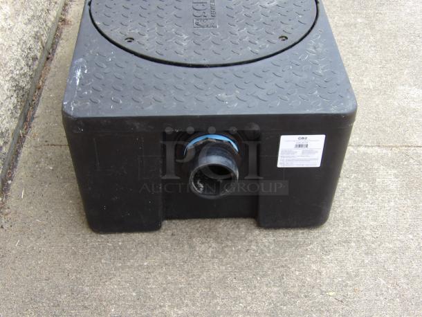 Black plastic grease trap with diamond tread lid, visible inlet pipe, and GB2 model label on side. Moderate wear.
