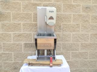 Stainless steel hand wash sink with Gojo soap dispenser, mounted on wooden platform. Good condition, ideal for commercial use.