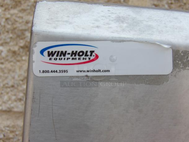 Win-Holt Equipment label on metal surface, showing contact number and website. Item appears used with slight wear.
