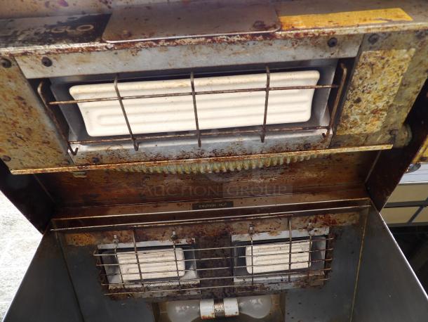 Rusty vintage outdoor heater with two ceramic elements and metal grates. "Caution: Hot" label. Wear and corrosion visible.