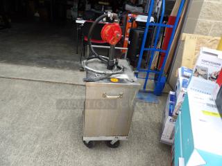 Mobile fuel pump unit on wheeled cart, features a red hand-crank pump, hose, and a metal tank. Used condition.