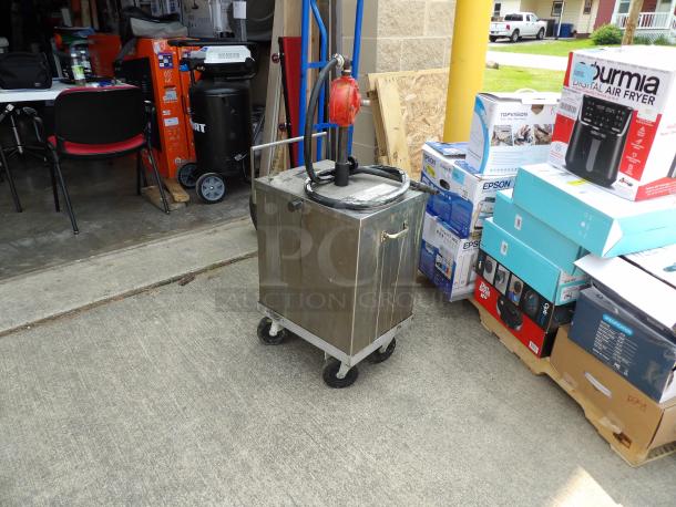 Commercial metal oil pump cart with attached red pump and hose on wheels, used condition. Suitable for bulk oil transfer.