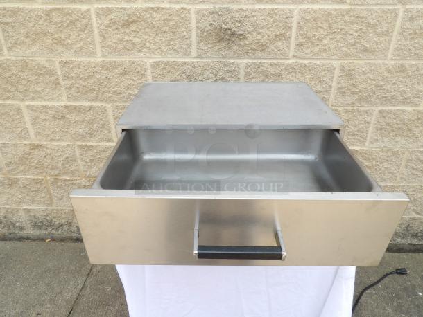 Stainless steel warming drawer, good condition, integral handle, no visible branding or labels, power cord attached.