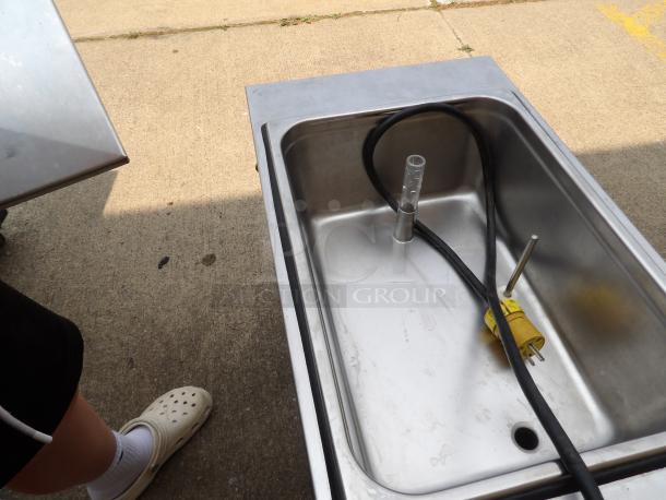 Stainless steel commercial sink with a yellow power plug and hose, used condition, ideal for catering or food prep.